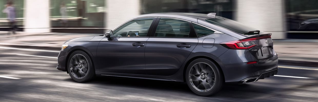 Gray 2023 Honda Civic Hatchback driving on a city street