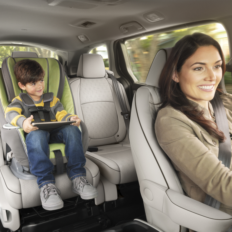 Woman driving with child in car seat. 
