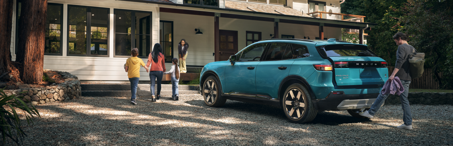 A family walking away from a 2025 Prologue vehicle towards a house.